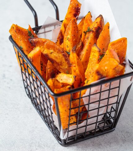Sweet potato fries in metal basket, gray background. Vegan food concept.