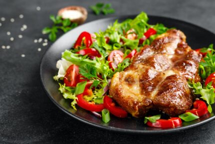 Baked pork steak with fresh vegetable salad on a plate